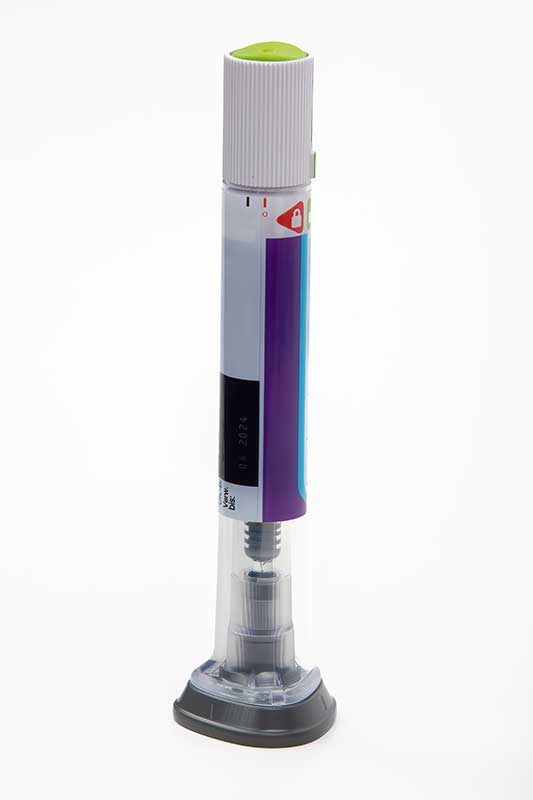 A gray and purple injection pen with a green cap and a transparent bottom section showing its internal mechanism.