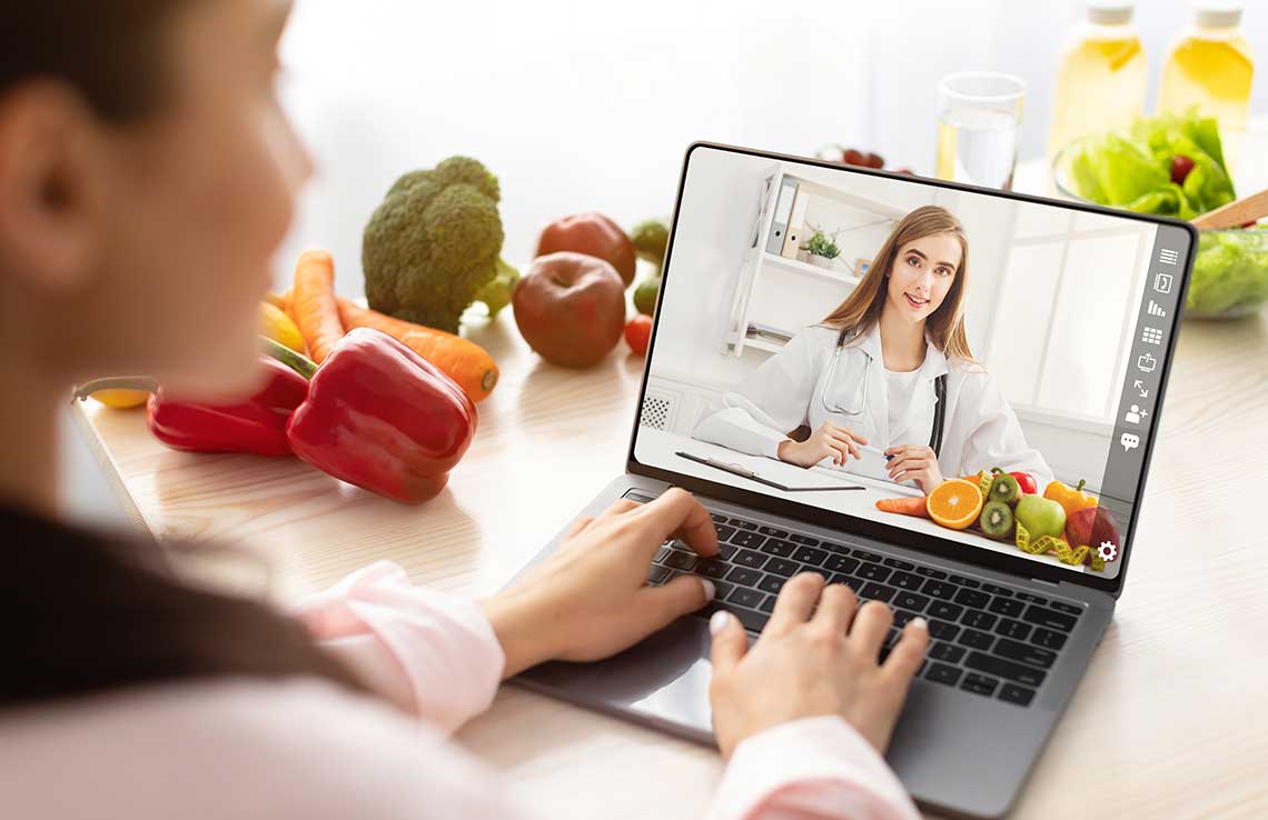 Person on a video call with a doctor surrounded by fresh vegetables.
