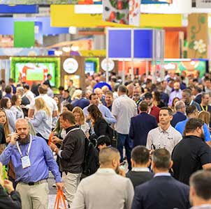 A crowded exhibition hall with people and colorful booths.